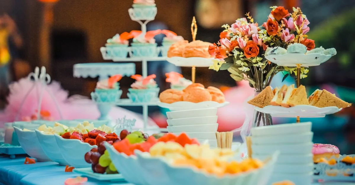 Table de dessert colorée avec une variété de fruits, gâteaux et décor floral, idéale pour les célébrations.