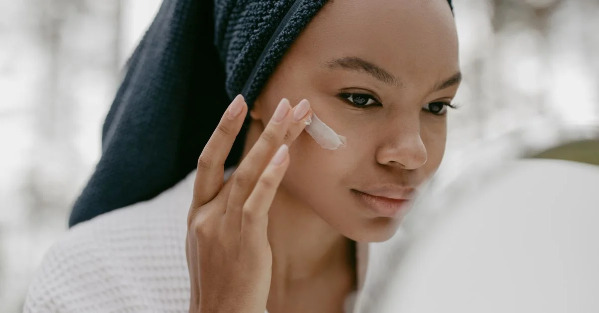 Femme appliquant délicatement de la crème pour le visage dans sa routine de soins, mettant l'accent sur une peau saine.
