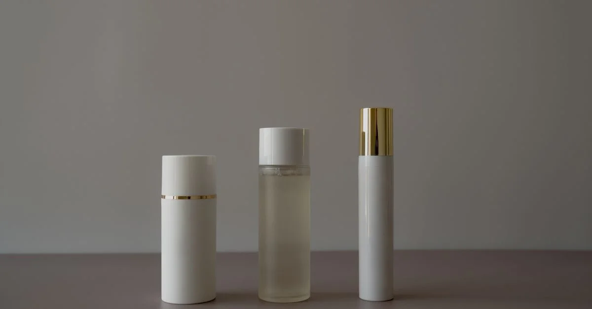 Agencement simple et minimaliste de flacons cosmétiques sur fond gris.