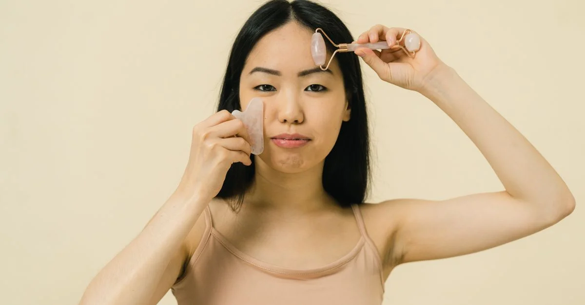 Femme asiatique utilisant un rouleau facial pour les soins de la peau et le bien-être dans un studio.